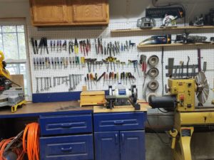 Wall of pegboard loaded with hand tools helps organize the woodshop by keeping handheld tools and visible.