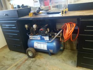 Air compressor setting under counter.  The hoses run along the wall behind the counter.