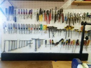 Wall of pegboard loaded with hand tools helps organize the woodshop by keeping handheld tools and visible.