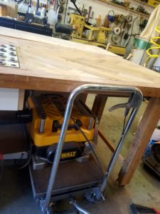 This tip to organize a small woodshop is to store tools like this plainer under a workbench using a hydraulic lift cart.